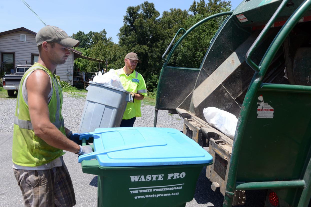 Waste Pro workers load trash into a rear-loading garbage trust. Sometimes seals can go bad in these trucks, resulting in trash 'juice' leaking onto roadways. Waste Pro inspects the trucks daily to prevent this from happening, though.