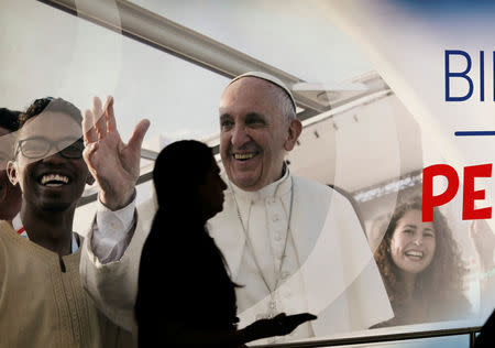 A passenger walks past a poster of Pope Francis at the Tocumen International Airport ahead of Pope Francis' visit for World Youth Day in Panama City, Panama January 21, 2019. REUTERS/Henry Romero