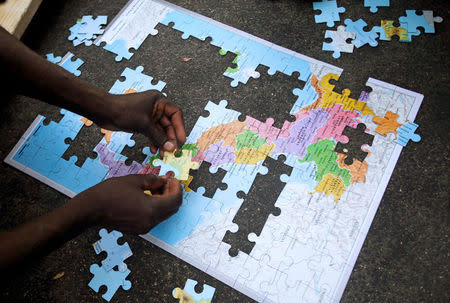 Migrants assemble a puzzle depicting Italy on a map, at a makeshift camp in Via Cupa (Gloomy Street) in downtown Rome, Italy, August 2, 2016. REUTERS/Max Rossi