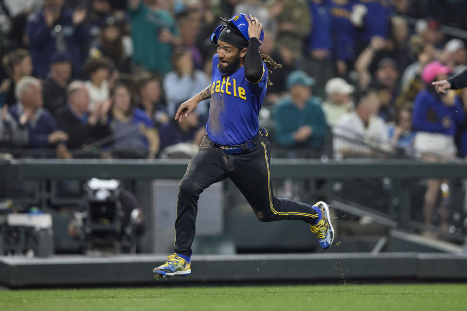 Seattle Mariners' J.P. Crawford runs home holding his batting helmet to score on a single by Ty France against the Chicago White Sox during the sixth inning of a baseball game Friday, June 16, 2023, in Seattle. (AP Photo/John Froschauer)