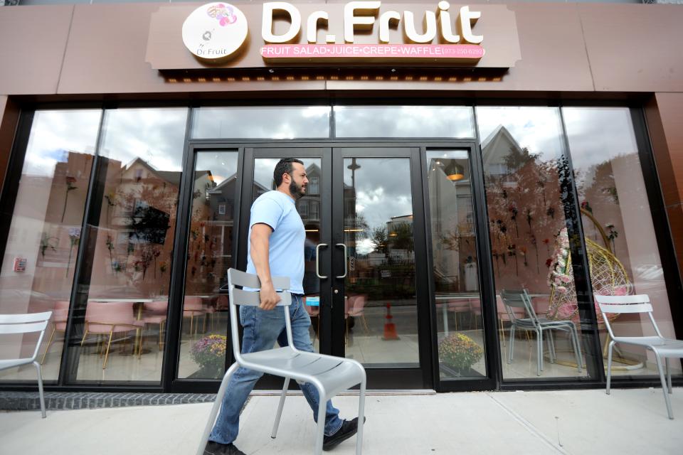 Feras Sasila sets up chairs outside Dr. Fruit, the South Paterson dessert spot he owns with his wife, Noura Oudeh. Sasila splits his days between working at the cafe, another job at a local car dealership and sharing parenting duties with Oudeh for their three children. Thursday, Sept. 30, 2021.
