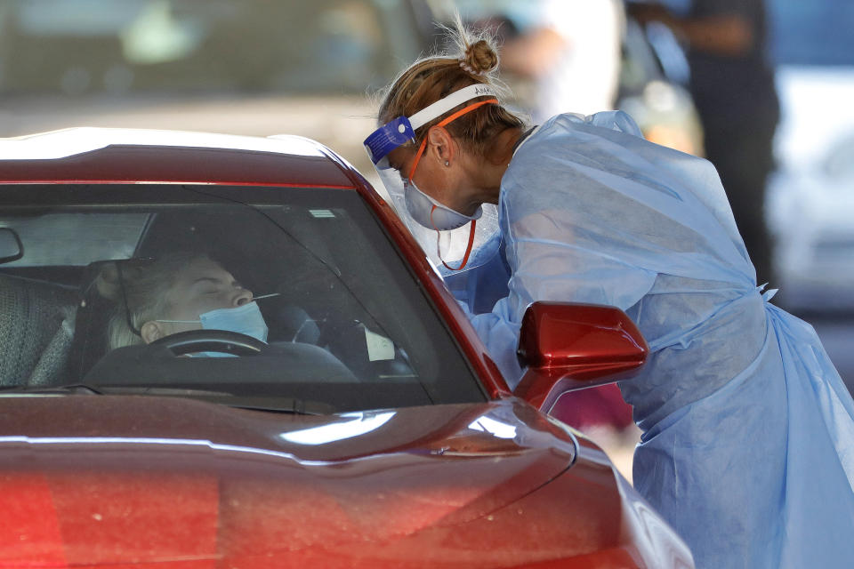 A person is tested for the COVID-19 Coronavirus Tuesday, July 28, 2020 at Cesar Chavez City Park in Phoenix. The two-week testing event is aimed at bringing tests to Phoenix's Laveen neighborhood, home to many Latinos and Blacks who have been disproportionately affected by the coronavirus. Latino leaders say governments need to do more to communicate effectively with Hispanic communities to ensure people know where to get tested and encourage them to participate. (AP Photo/Matt York)