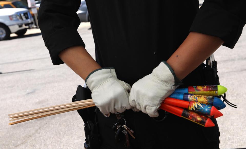 A man with gloves handles fireworks.