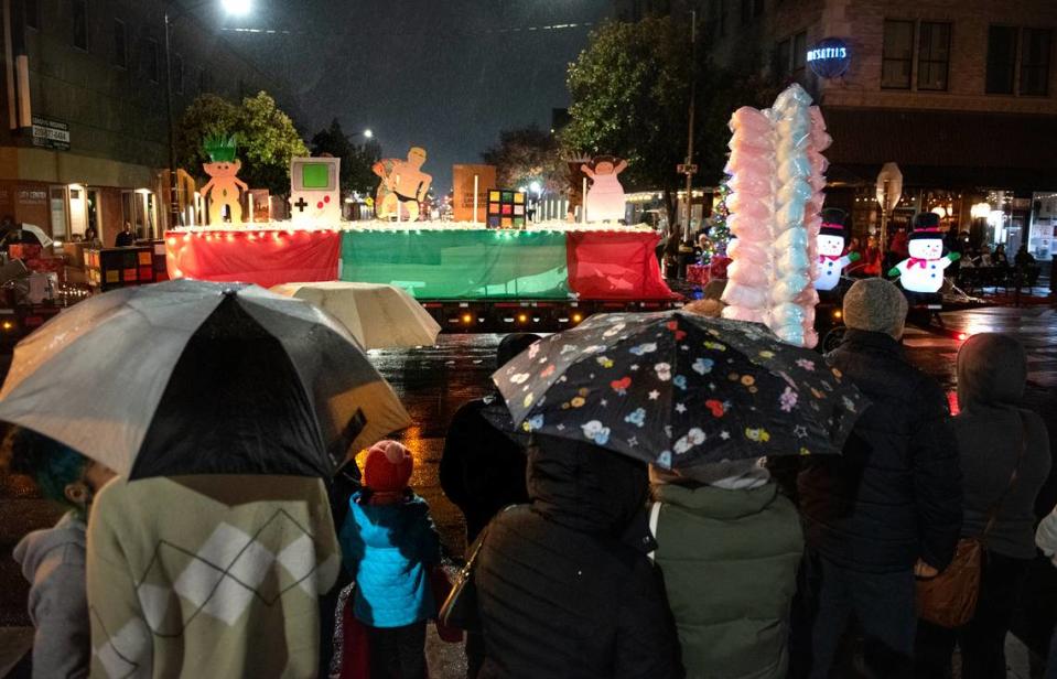 Rain falls as people watch the Celebration of Lights holiday parade on J Street in Modesto, Calif., Saturday, Dec. 3, 2022.