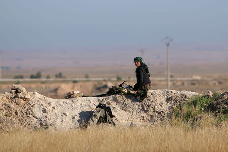 A fighter from the Democratic Forces of Syria sits at a guard post in the 121 Regiment base, after the group took control of it from Islamic State militants, in the town of al-Melabiyyah, south of Hasaka city, Syria November 24, 2015. REUTERS/Rodi Said