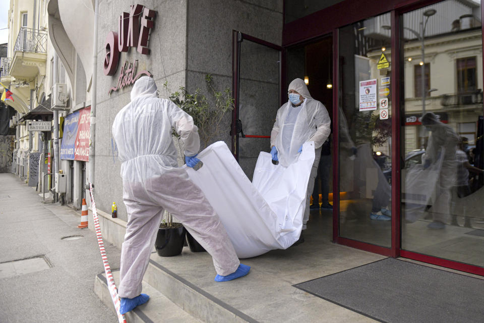 Forensic workers carry the body of Gholamreza Mansouri from a hotel downtown Bucharest, Romania, Friday, June 19, 2020. Mansouri, a former judge from Iran sought by his country to face corruption charges has died after falling from a high floor inside a hotel. Romanian police said only that a man had fallen from a high floor at a hotel in Bucharest, the Romanian capital, and was found dead. (AP Photo/Andreea Alexandru)