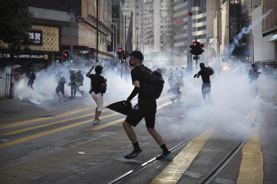 FILE - In this Saturday, Nov. 2, 2019, file photo, pro-democracy protesters react as police fire tear gas during a protest in Hong Kong. By day, the small commercial kitchen in a Hong Kong industrial building produces snacks. At night, it turns into a secret laboratory assembling a detox kit to help frontline pro-democracy protesters counter ill-effects from repeated exposure to tear gas. (AP Photo/Kin Cheung, File)