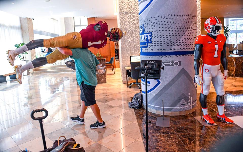 Employees remove mannequins dressed for each team as the ACC Kickoff Media Days event closes in downtown Charlotte, N.C. Thursday, July 27, 2023.