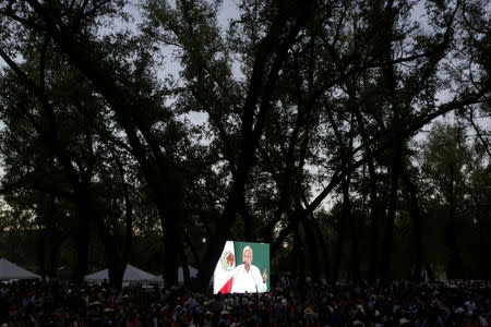 People watch Mexico's President Andres Manuel Lopez Obrador on a video screen during an event in Badiraguato, in the Mexican state of Sinaloa, Mexico February 15, 2019. REUTERS/Daniel Becerril