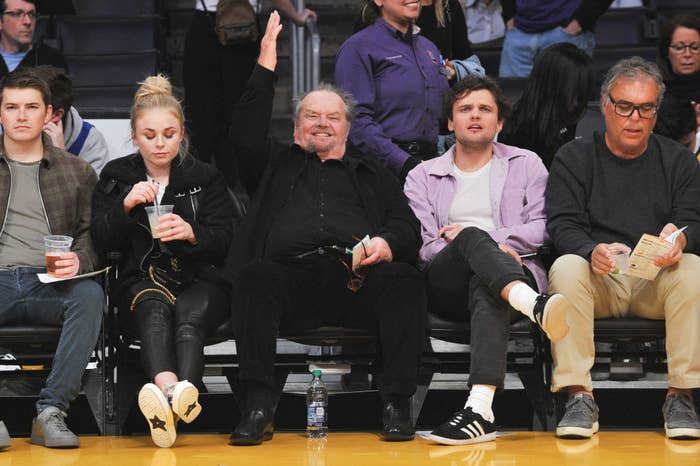 Jack sitting courtside at a basketball game with his arms raised