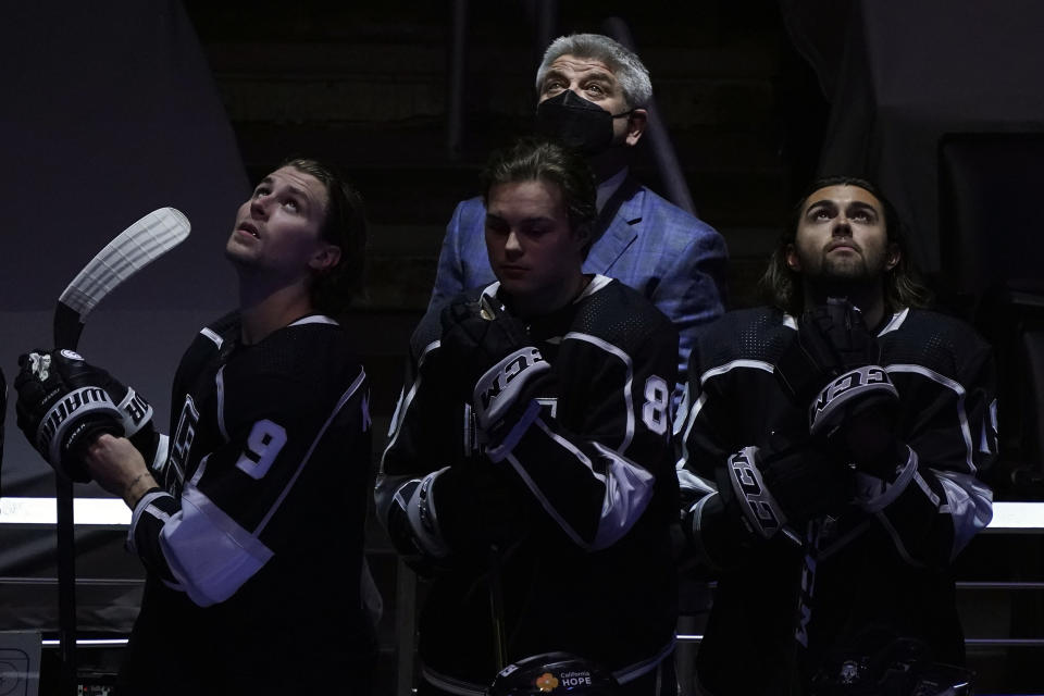 Los Angeles Kings head coach Todd McLellan, top, looks up during the national anthem along with some of his players before an NHL hockey game against the St. Louis Blues, Friday, March 5, 2021, in Los Angeles. (AP Photo/Marcio Jose Sanchez)