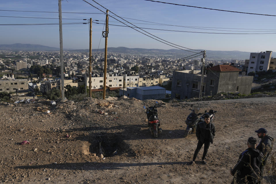 Palestinians inspect the site where a roadside bomb killed one Israeli paramilitary police officer and injured three others during overnight clashes in the Jenin refugee camp, West Bank, on Sunday, Jan. 7, 2024. Six Palestinians and a member of Israel's paramilitary border police were killed in confrontations in a hot spot of violence in the Israeli-occupied West Bank, the Palestinian Health Ministry and the Israeli military said Sunday. (AP Photo/Majdi Mohammed).