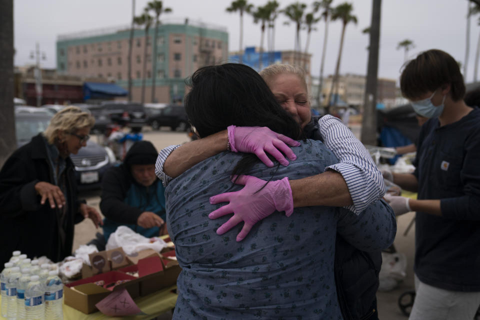 Pamela Connoly, facing camera, CEO and founder of Hope for the Hearts of the Homeless, hugs Melissa Acedera of Polo's Pantry while serving meals to homeless people in the Venice neighborhood of Los Angeles, Tuesday, June 29, 2021. (AP Photo/Jae C. Hong)