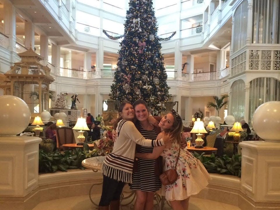 hayley and friends posing in front of the grand floridian Christmas tree at disney world