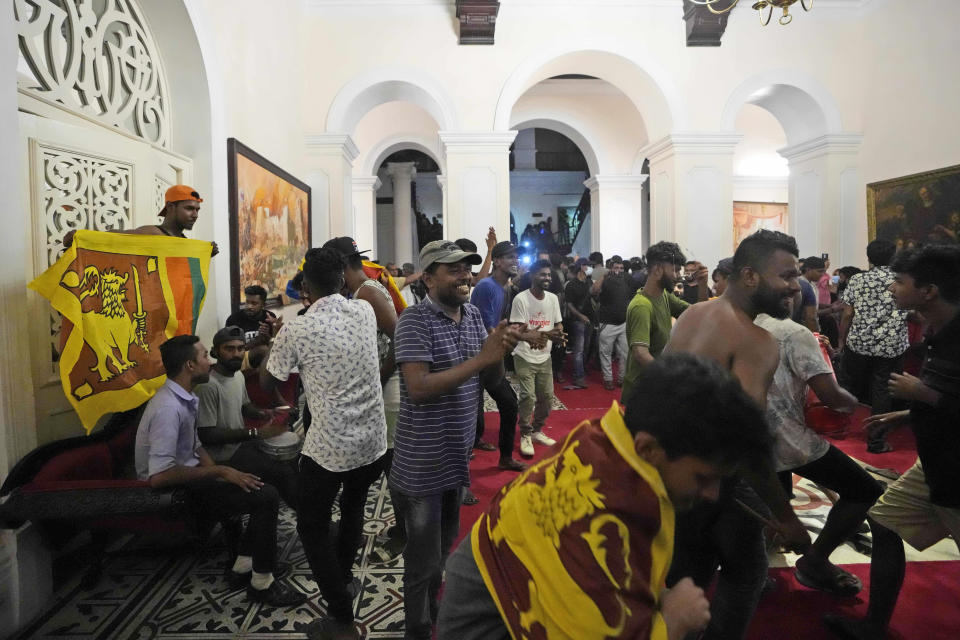 Protesters sing and dance after storming in at the Sri Lankan president official residence, in Colombo, Sri Lanka , Saturday, July, 9, 2022. Protesters have broken into the Sri Lankan prime minister's private residence and set it on fire, hours after he said he would resign when a new government is formed over a worsening economic crisis. It was the biggest day of demonstrations that also saw crowds storming the president's home and office. (AP Photo/ Eranga Jayawardena)