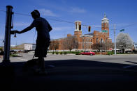 An empty town square is seen as a teenager pushes a crosswalk button as he walks his dog, Thursday, April 2, 2020, in Greensburg, Ind. (AP Photo/Darron Cummings)