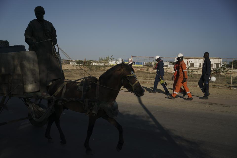 Workers walk toward a local hotel after arriving from the offshore gas terminal in Saint Louis, Senegal, Friday, Jan. 20, 2023. Senegalese officials and the gas companies say people should be patient, as jobs and benefits from the gas deal will materialize. (AP Photo/Leo Correa)