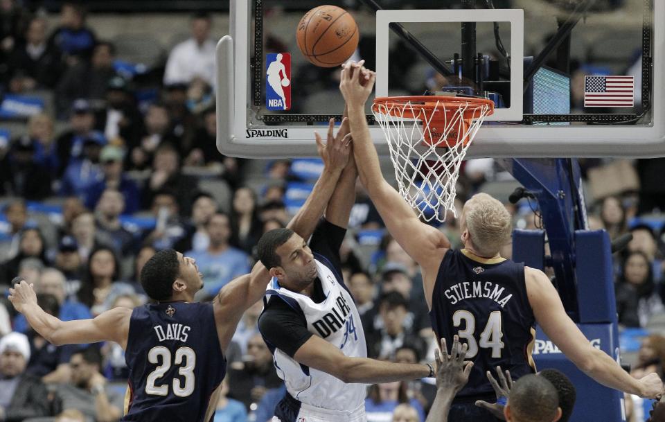 Dallas Mavericks' forward Brandan Wright, center, battles New Orleans Pelicans' Anthony Davis (23) and Greg Stiemsma, right, for a rebound during the first half of an NBA basketball game on Wednesday, Feb. 26, 2014, in Dallas. (AP Photo/Brandon Wade)