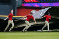 Members of the Atlanta Braves grounds crew rush to cover the infield during a rain shower in the first inning of the Braves' baseball game against the San Francisco Giants on Friday, Aug. 27, 2021, in Atlanta. (AP Photo/John Bazemore)