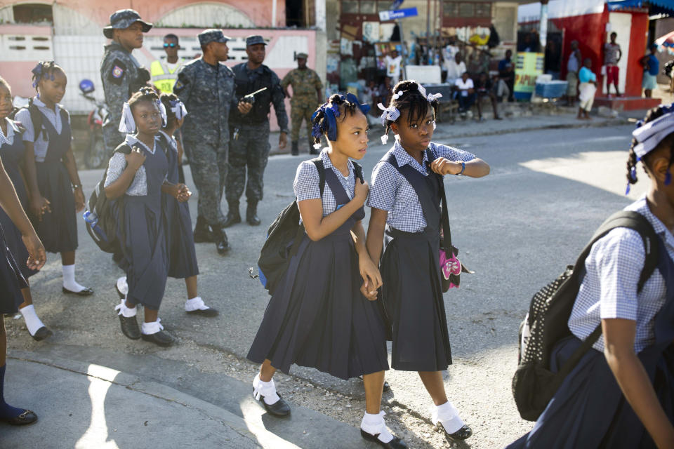 In this Sept. 3, 2018 photo, students arrive hand in hand to the Brazilian National School before the start of a ceremony marking the first day back to class in Port-au-Prince, Haiti. (AP Photo/Dieu Nalio Chery)