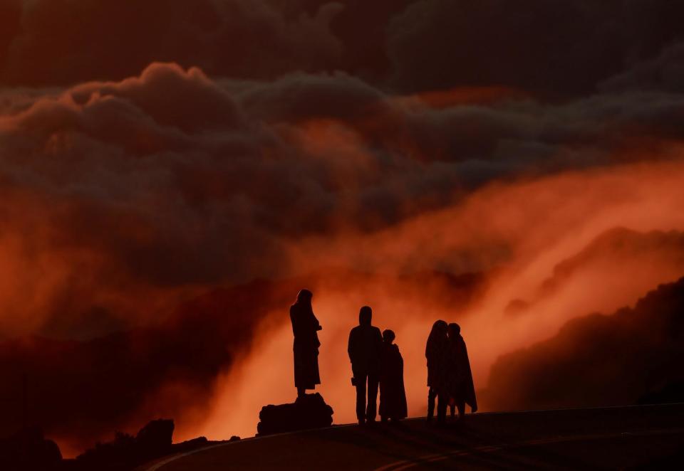 Light illuminates clouds as people watch the sunrise at Haleakala National Park in Hawaii: REUTERS/Navesh Chitrakar