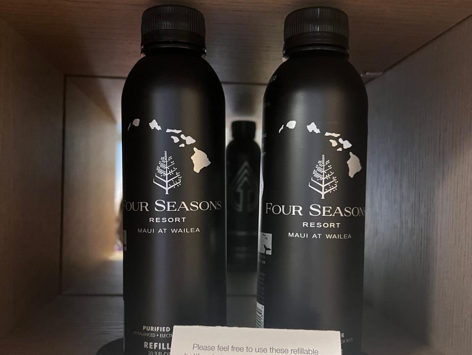 Two black, aluminum bottles of water with a note and a black marker.