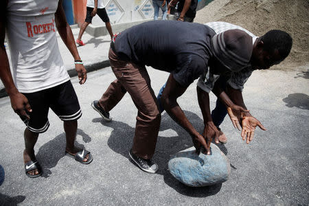 Demonstrators move a rock to block a street during a protest in Port-au-Prince, Haiti, July 14, 2018. REUTERS/Andres Martinez Casares