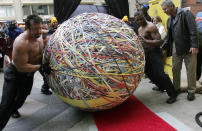 Workers roll a rubberband ball to a scale for certification of weight during a Guinness Book of World Records official weigh-in in Chicago November 21, 2006. The 4,594 pound (2,084 kg) ball beat the previous record of 3,120. REUTERS/Frank Polich