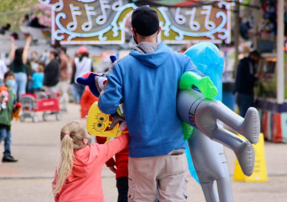 A pair of lucky guests walk away from the Tulip Time carnival's games with an armful of prizes Saturday, May 1, 2021.