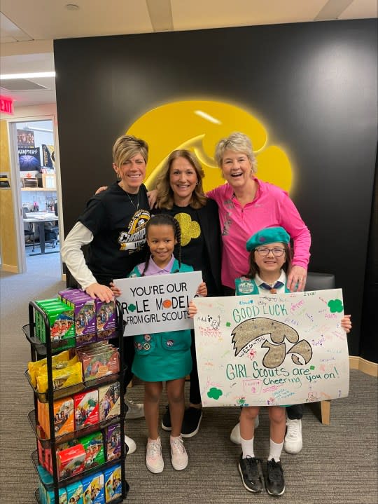 Jan Jensen, left, Associate Head Coach for Iowa Women’s Basketball, Diane Nelson, CEO for Girl Scouts of Eastern Iowa and Western Illinois, and Lisa Bluder, Head Coach for Iowa Women’s Basketball. In front, Girl Scouts Kaliana Woods and Lilly Smith from Troop 2405 proudly show their signs to cheer on the team.