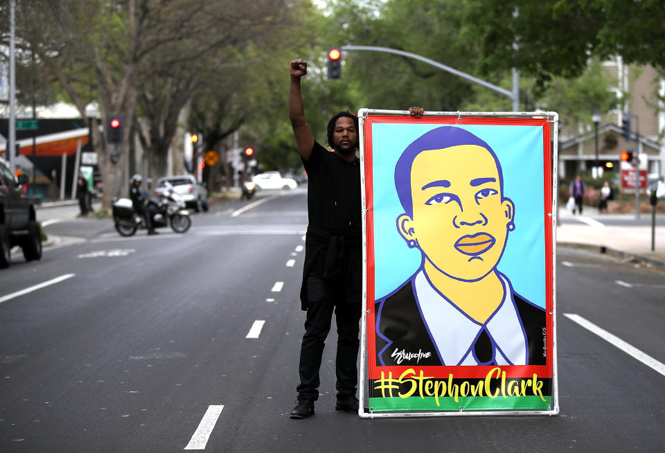 A Black Lives Matter protester holds an illustration of Stephon Clark.