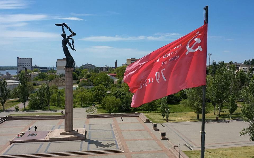 A replica of the Soviet Banner of Victory flies by a WWII memorial in Kherson which was the first major city to fall to Russian forces - AFP