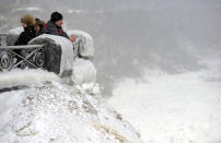 Visitors observe the falls in Niagara Falls, Ontario, January 8, 2014. The frigid air and "polar vortex" that affected about 240 million people in the United States and southern Canada will depart during the second half of this week, and a far-reaching January thaw will begin, according to AccuWeather.com. REUTERS/Aaron Harris (CANADA - Tags: ENVIRONMENT TRAVEL)