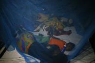 Displaced victims of Cyclone Idai, sleep under a mosquito net at the Samora Machel Secondary School which is being used to house victims of the floods in Beira, Mozambique, Sunday March 24, 2019. The death toll has risen above 750 in the three southern African countries hit 10 days ago by the cyclone storm, as workers restore electricity, water and try to prevent outbreak of cholera, authorities said Sunday. (AP Photo/Phill Magakoe)