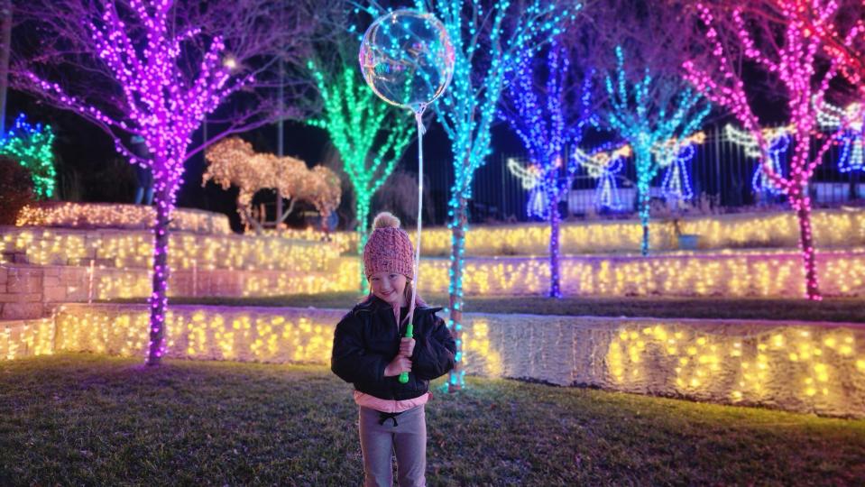 Ava Stewart stands with a glowing balloon Thursday night at the Amarillo Botanical Gardens during its Christmas in the Garden event.