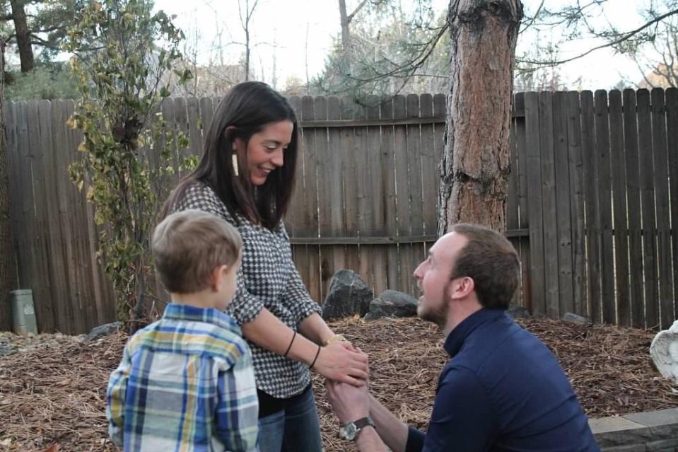 Nick is kneeling on the ground, proposing to Katie