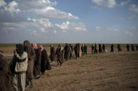 Men walk to be screened by U.S.-backed Syrian Democratic Forces (SDF) fighters after being evacuated out of the last territory held by Islamic State militants, near Baghouz, eastern Syria, Friday, Feb. 22, 2019. (AP Photo/Felipe Dana)