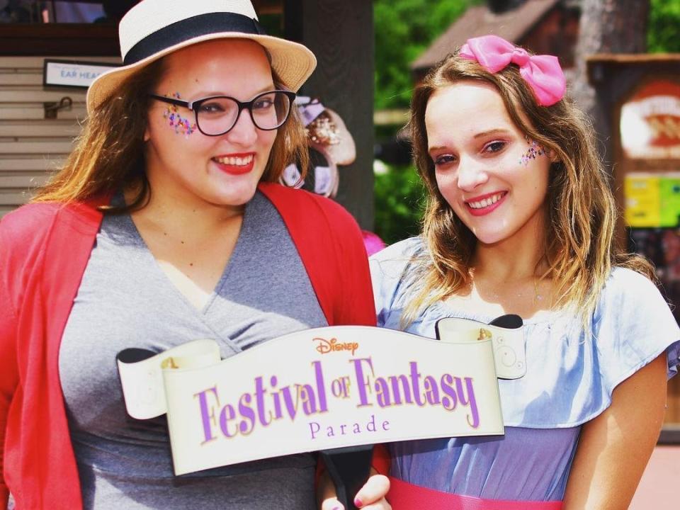 casey posing holding the sign for festival of fantasy parade at disney world