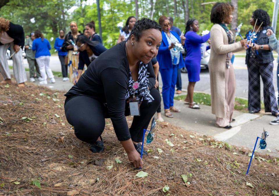 Rodana Bonner a DHHS employee plants a pinwheel along Departure Drive to raise awareness to child abuse prevention on Wednesday, April 17, 2024 in Raleigh, N.C.