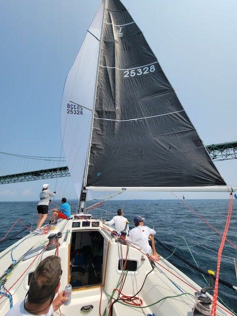 The crew of Hot Ticket races toward the finish line of the Chicago to Mackinac race on Monday, July 24, 2023. This image is taken by crew member Tom Schulte of Casco. Lynn Kotwicki of Royal Oak, standing far left, is trimming the sail with the Mackinac Bridge in the background. The J/120 sailboat owned by Michael Kirkman of Novi won its class.