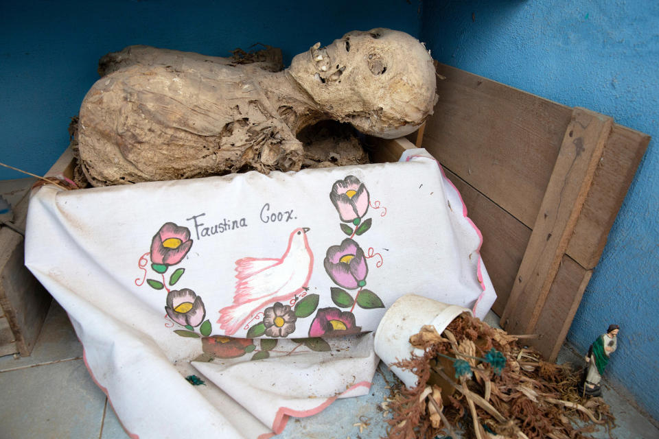 A dried-up skull and bones are seen wrapped in an embroidered white tablecloth bearing the name of the deceased, and placed in a wooden crate inside a niche at the cemetery in Pomuch on Oct. 22, 2022.