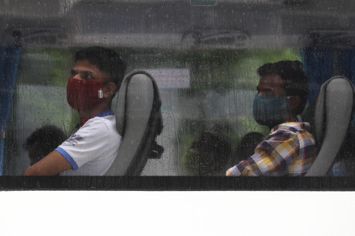 SINGAPORE - APRIL 27:  Foreign workers wearing protective masks wait on a bus to be transferred from their dormitory on April 27, 2020 in Singapore. Singapore is now battling to control a huge outbreak in the coronavirus (COVID-19) local transmission cases among the migrant workers.  (Photo by Suhaimi Abdullah/Getty Images)