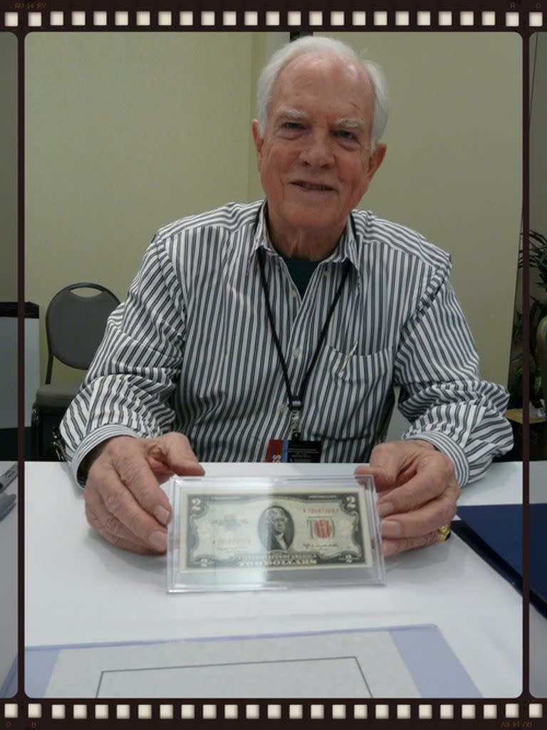 El comandante del Apolo 15 y el caminante lunar David Scott sosteniendo el billete de $ 2 volado en la reunión de la Fundación de Becas de Astronautas en noviembre de 2008, por Jefferson Space Museum