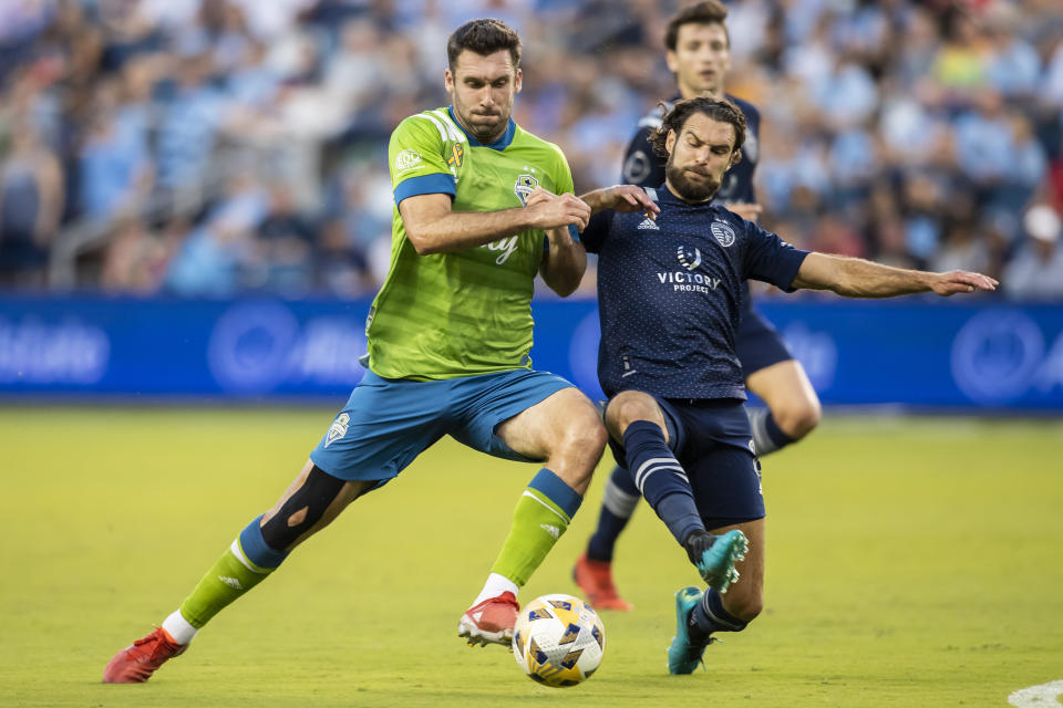 Sporting Kansas City midfielder Graham Zusi knocks the ball away from an attacking Seattle Sounders defender Will Bruin during the first half of an MLS soccer match Sunday, Sept. 26, 2021, in Kansas City, Kan. (AP Photo/Nick Tre. Smith)