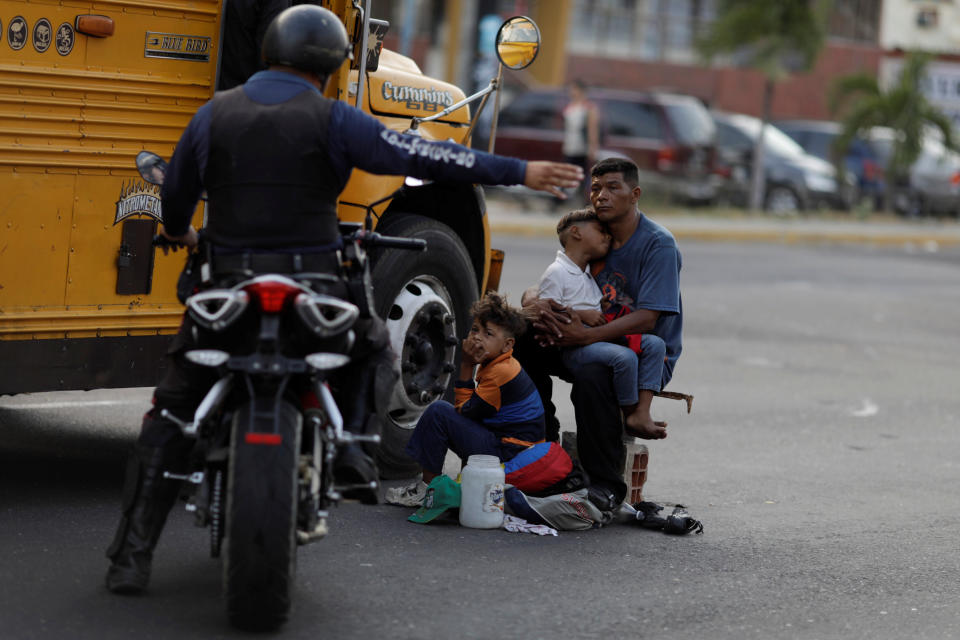A Venezuelan police officer orders a man and his sons to move from the street where he was asking for donations during a blackout in Maracaibo, Venezuela. (Photo: Ueslei Marcelino/Reuters)