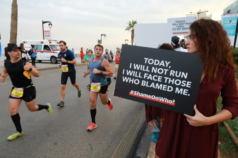 Activists hold placards to call for tougher action against sexual assault during Beirut's marathon on November 11, 2018