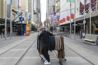 A department store employee wheels clothes across the Bourke Street Mall as retail businesses prepare to close their doors to walk-in customers as lockdown of Melbourne forces people to stay at home if not working due to the continuing spread of the coronavirus, Wednesday, Aug. 5, 2020. Victoria state, Australia's coronavirus hot spot, announced on Monday that businesses will be closed and scaled down in a bid to curb the spread of the virus. (AP Photo/Asanka Brendon Ratnayake)