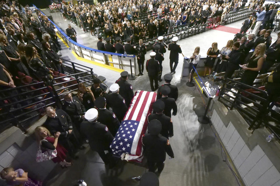 Firefighters carry the casket of Battalion Chief Matt Burchett of the Draper Fire Department into the Maverik Center during funeral services Monday, Aug. 20, 2018, in West Valley City, Utah. Burchett died while fighting a wildfire north of San Francisco. He was flown to a hospital where he succumbed to his injuries. (AP Photo/Rick Bowmer)