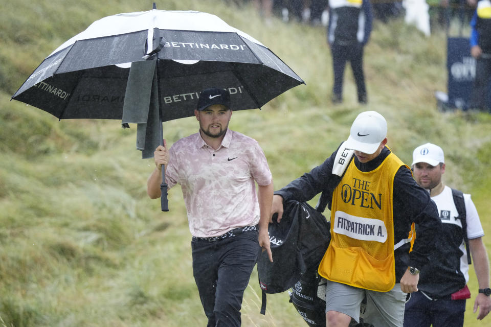 England's Alex Fitzpatrick shelters under an umbrella as he walks from the 14th tee during the final day of the British Open Golf Championships at the Royal Liverpool Golf Club in Hoylake, England, Sunday, July 23, 2023. (AP Photo/Jon Super)