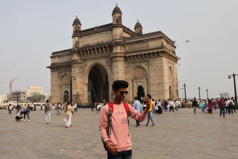 21-year-old aspiring college student and migrant worker Sujeet Kumar shoots a video on his mobile phone in front of the Gatewat of India monument in Mumbai